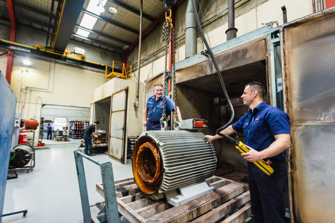 EMSS employees hoisting an electric motor on chains in the workshop
